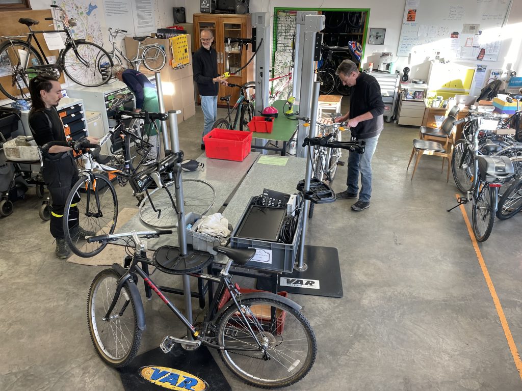 Des bénévoles et adhérents s'affairent a réparer des vélos dans les locaux du Maillon Solidaire.